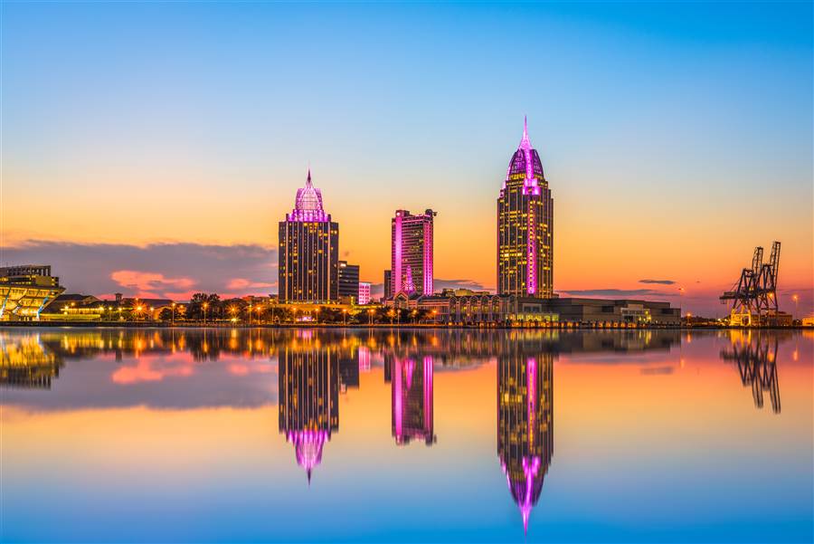 Mobile, Alabama skyline lit up at sunset with port cranes