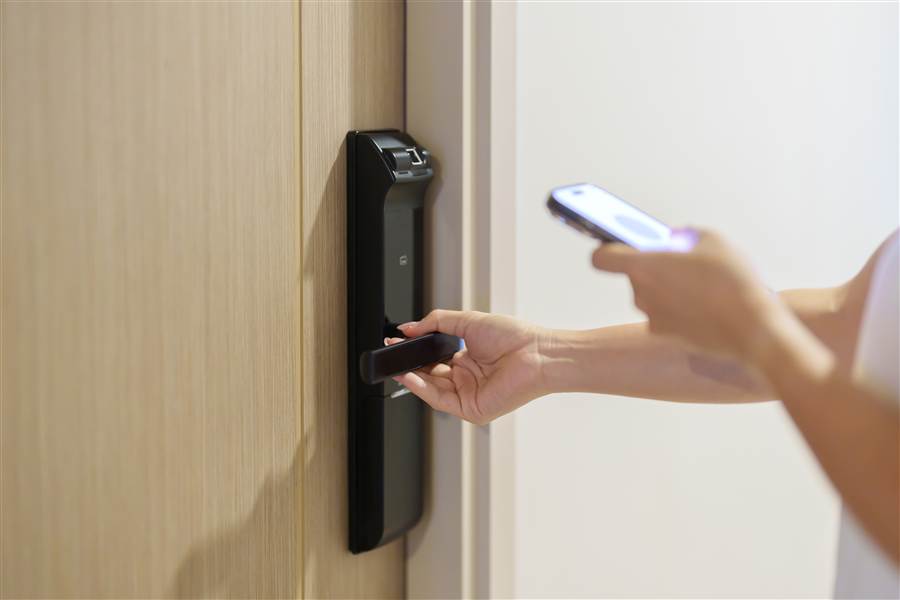 Guest unlocking a hotel room door with a mobile phone