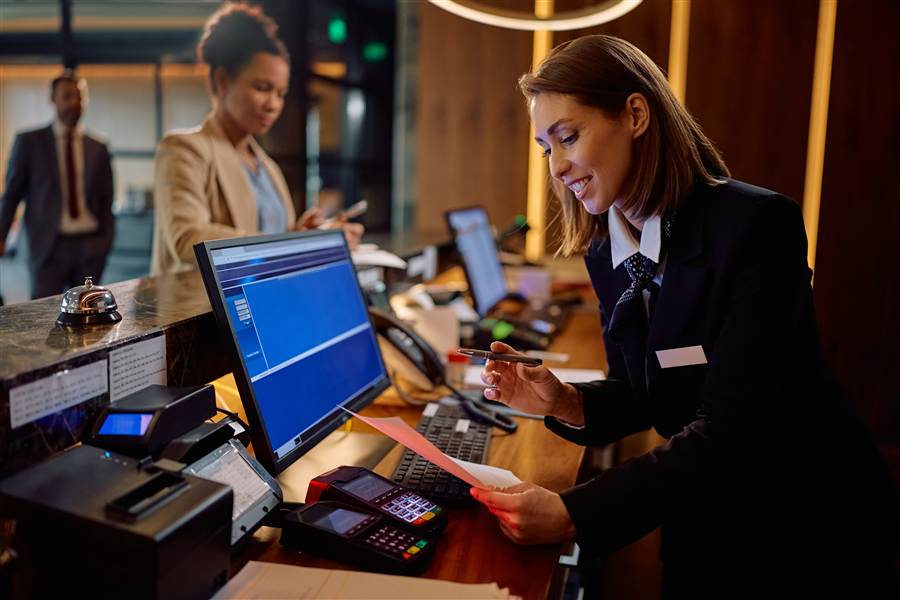 Hotel front desk agent checking in a guest using PMS software