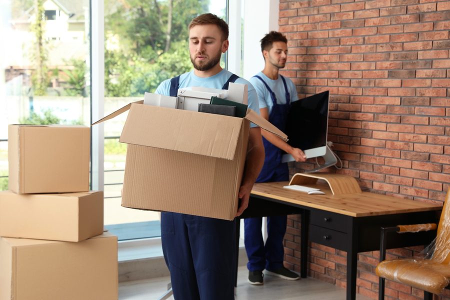 Movers carrying boxes and a computer monitor during an office relocation
