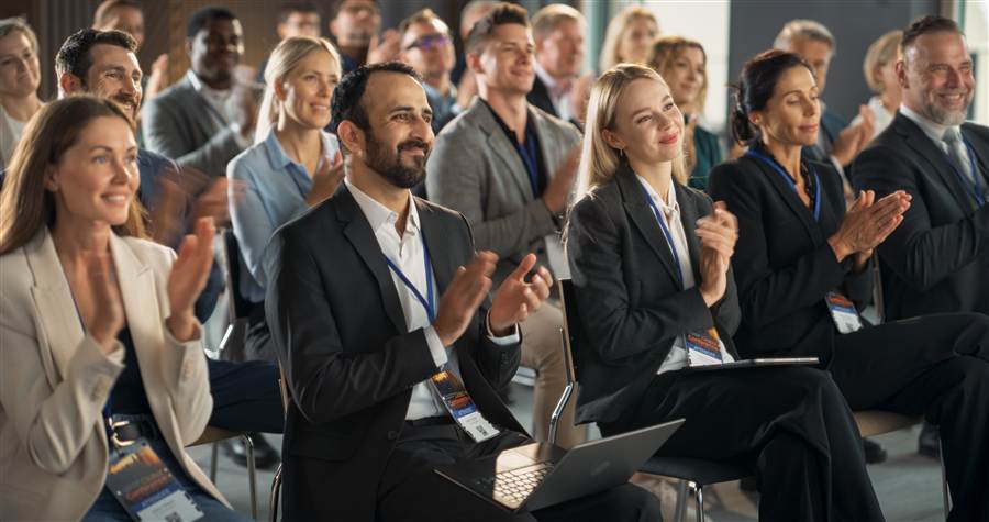Conference attendees applauding at a large event