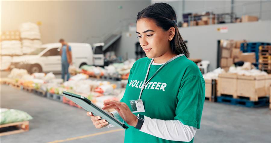 Nonprofit volunteer using a tablet to track donated goods in a warehouse