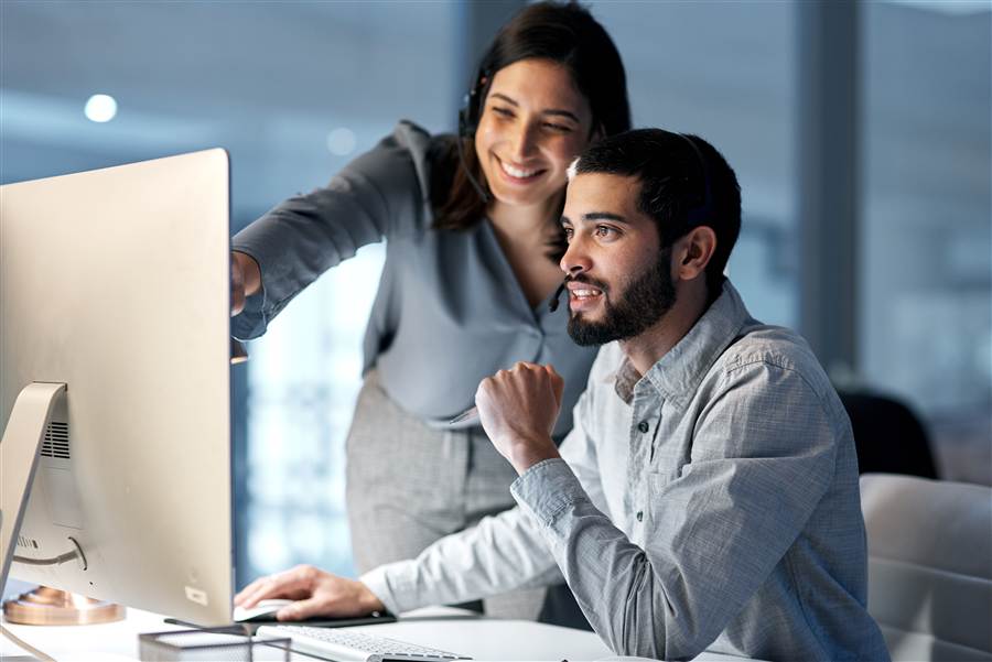 Support technician pointing out something on a coworker's desktop screen