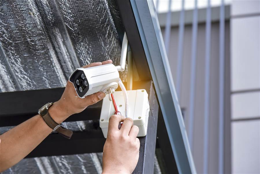 Technician installing a security camera under a building eave